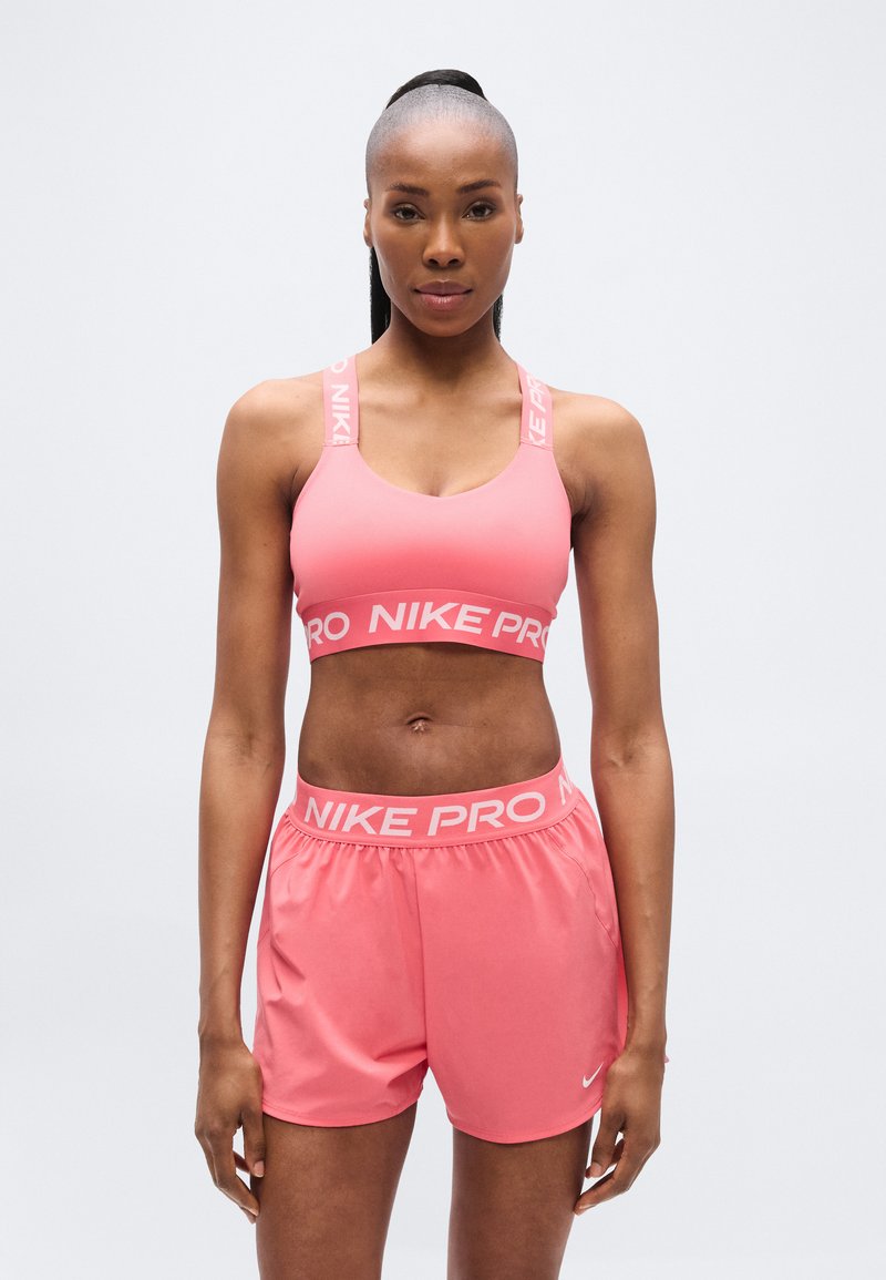 Ροζ αθλητικό σουτιέν και αντίστοιχο σορτς από λείο, ελαφρύ υλικό, με τη σήμανση "NIKE PRO" στα λουριά και τη μέση.