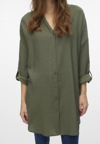 Camicia verde oliva dal taglio morbido, realizzata in tessuto leggero, con scollatura a V, chiusura frontale con bottoni e maniche arrotolate.