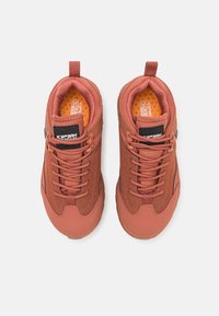 Rostfargede sneakers med teksturert stoff, rund tå og snøring. Har en polstret krage og kontrasterende oransje innersåle.