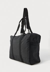 Crni pravokutni torba za duffel s dvostrukim ručkama za nošenje i podesivom naramenicom na bijeloj pozadini.