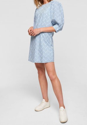 Hellblaues kurzes Kleid mit weißem Streifenmuster, Puffärmeln, einem runden Ausschnitt und einem lockeren Schnitt. Trägt dazu cremefarbene Sneaker.