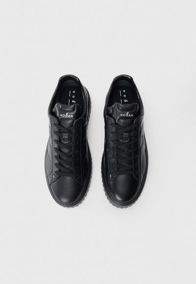 Pair of black leather Hogan sneakers with black laces, thick soles, and white branding on tongue against a plain white background.