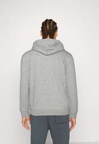 Sudadera gris con una gran capucha ajustable, puños y cintura acanalados, confeccionada con una suave tela texturizada para mayor comodidad.