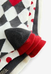 Kolorowe skarpetki z wzorem w romby w odcieniach szarości, bieli i czerwieni. Wykonane z miękkiego dzianinowego materiału z prążkowanymi ściągaczami, prezentujące wyraźne ukośne kształty.