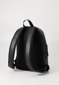 Zaino nero con esterno in pelle liscia e pannelli posteriori in rete. Include spallacci imbottiti e una maniglia superiore per un maggiore comfort.