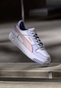 Puma tenisice s bijelim, ružičastim i svijetloplavim kožnim gornjištem, s teksturiranom potplatom i logotipom, prikazujući nisku dizajn.