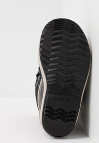 Czarna gumowa podeszwa sportowa z zygzakowatym wzorem bieżnika, z gładką białą podeszwą środkową i wytłoczonym logo "SOREL" na pięcie.