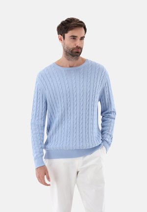 Light blue cable knit sweater with a round neckline and ribbed cuffs, featuring a textured pattern and relaxed fit. Paired with white trousers.