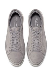 Pár šedých tenisek Cole Haan Grandseries s tkaničkami, zobrazených z vrchu na bílém pozadí.