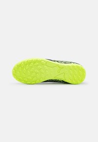 Football shoe outsole with yellow rubber material, featuring a textured pattern and distinct grip studs. Predominantly black design accents.