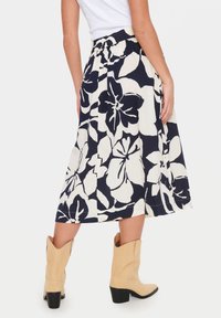 En marinblå och krämfärgad blommig kjol med ett flytande design och elastisk midjeband, kombinerad med ljusbeige ankelboots.