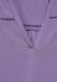 Lila Stoffoberteil mit V-Ausschnitt. Verfügt über feine Stickdetails und horizontale Ösenakzente. Glatte Textur mit leichtem Erscheinungsbild.