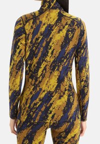Langärmliges Oberteil mit hohem Kragen, aus strukturiertem Stoff mit einem gelb-blauen abstrakten Muster, figurbetontem Design und flachen Nähten.