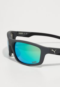 Lunettes de sport avec une monture en gris mat, des verres miroir bleu-vert et un petit logo Puma argenté sur la branche.
