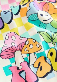 Spalvota medžiaga su animaciniu stiliumi pieštomis grybais rožinės, oranžinės ir baltos spalvų, kartu su gėlėmis ir geometriniais raštais ant languoto fono.