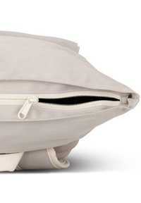 Canvas bag with a folded top, featuring a white zipper opening against a light beige background; textured fabric and sturdy stitching.
