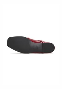 Red leather dress shoe viewed from the sole, showing smooth black outsole with CG logo and size imprint.
