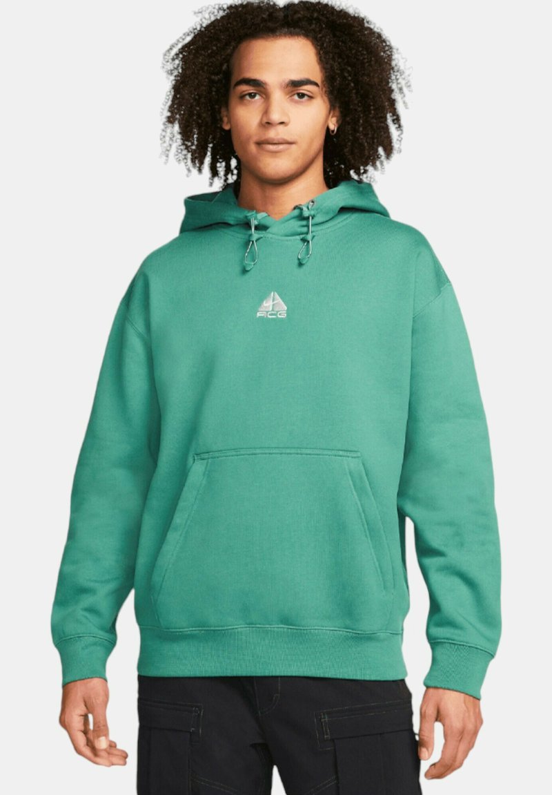 Grön bomullshuvtröja med framficka, justerbar dragsko och liten logotyp på bröstet. Slät textur och avslappnad passform.