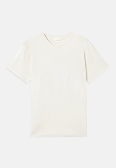 Rövid ujjú, kerek nyakú póló világos bézs színben, puha pamut anyagból készült, laza fazonú, látható minták vagy díszítések nélkül.