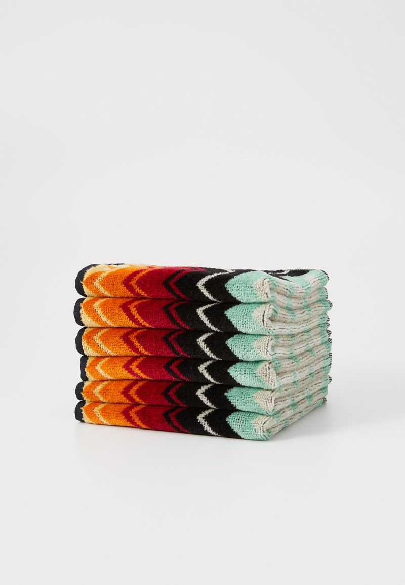 Un ensemble de six chaussettes tricotées empilées verticalement, avec des motifs en zigzag dans des couleurs vives : orange, rouge, noir et turquoise avec des accents gris.