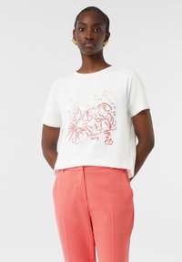 Weißes Kurzarm-T-Shirt mit rotem Hummer-Graphic und dem Text "Hummer-Party". Getragen mit rosa maßgeschneiderten Hosen aus glattem Stoff.