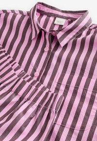 Pinker und brauner gestreifter Hemd mit Kragen, Knopfverschluss und Rüschendetails. Hergestellt aus einem glatten Baumwollstoff.
