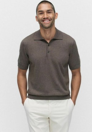 Brown short-sleeve polo shirt with a collar, featuring three black buttons and a fitted design, paired with light-colored trousers.