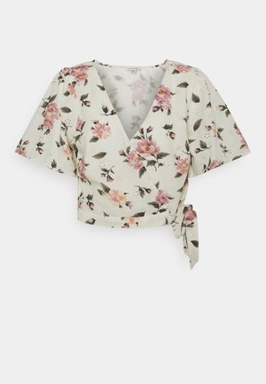 Blusa corta estilo envolvente en crema con estampado floral rosa, mangas cortas y anchas, y lazo lateral en la cintura.