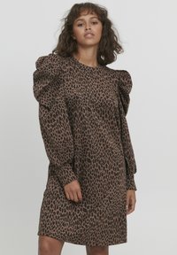 Robe en imprimé léopard avec des manches bouffantes, un col rond, une coupe décontractée, et des tons bruns sur un tissu léger. Texture lisse, longueur genoux.