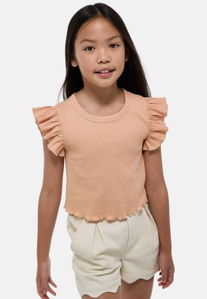 Top côtelé pêche à manches courtes avec des accents volantés et un col arrondi, associé à un short crème taille haute avec un ourlet en forme de vagues.