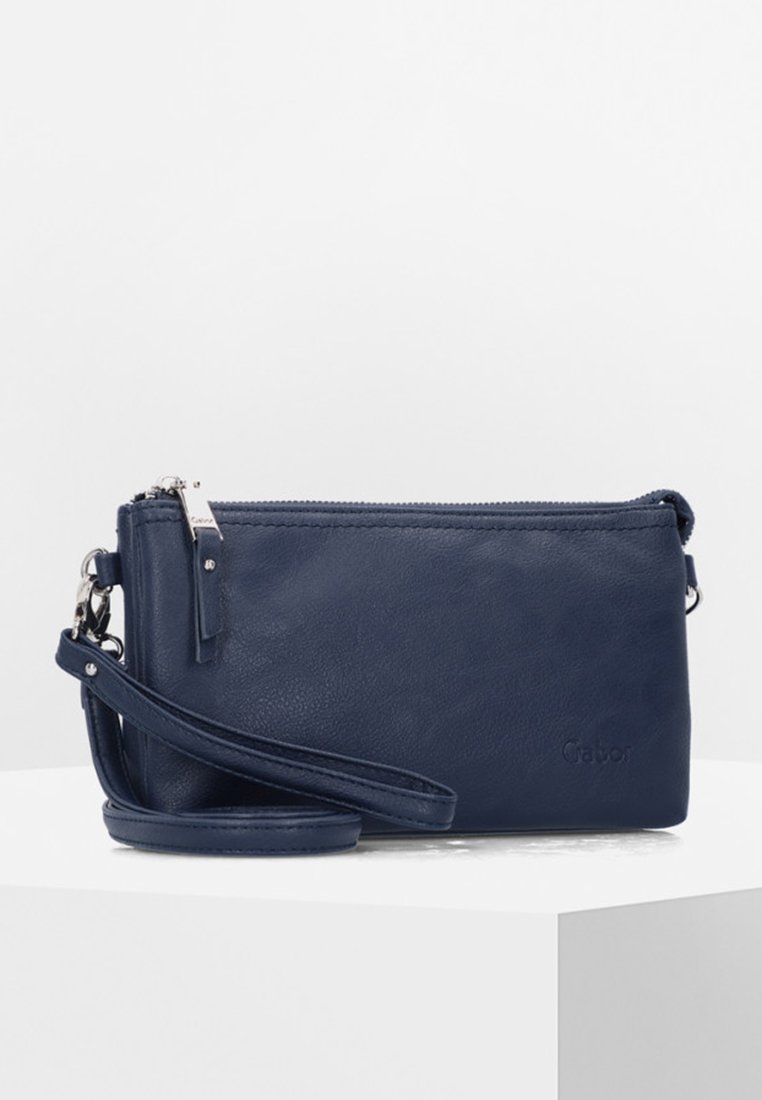 Marineblauwe leren schoudertas met een ritssluiting, enkele verstelbare schouderriem, subtiel logo en een gladde textuur. Compact rechthoekig ontwerp.