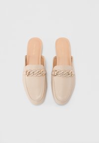Beige Leder-Mules mit flacher Sohle, zum Hineinschlüpfen und einem dekorativen Kettenakzent im Zehenbereich. Glatte Textur.
