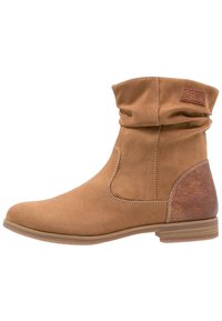 Helle Wildleder-Ankleboots mit einem lockeren Schaft, seitlichen elastischen Einsätzen und einem strukturierten braunen Akzent an der Ferse. Flache Gummisohle, gestickte Details.