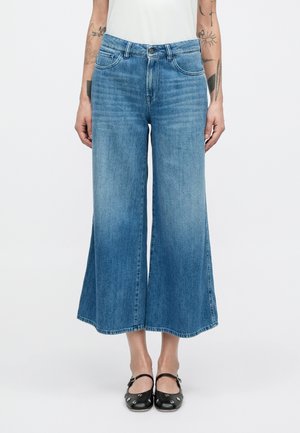 Széles szárú kék farmernadrág, világostól sötétig terjedő árnyalatgradienssel, öt zsebbel és gombos záródással; az anyag enyhén texturált felületű.