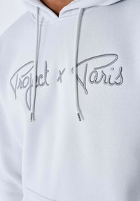 Felpa bianca con cappuccio caratterizzata da scritte ricamate grigie "Project x Paris", con cordini regolabili e punte in metallo. Tessuto morbido.