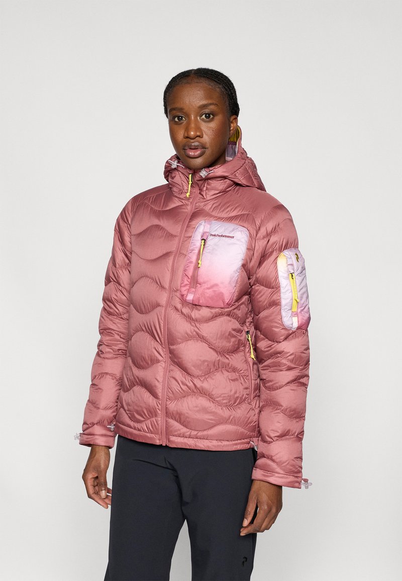 Ροζ μπουφάν με επένδυση και κουκούλα, με ραμμένη υφή, κίτρινους φερμουάρ και τσέπες με διαβάθμιση χρωμάτων. Κατάλληλο για υπαίθριες δραστηριότητες.