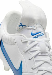 Botas de fútbol Nike Premier en cuero blanco con acentos en azul, punta redondeada y textura perforada; cuenta con un cuello acolchado y cordones.