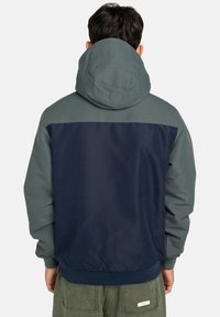 Giacca con cappuccio caratterizzata da un design bicolore con corpo blu navy scuro e spalle grigio chiaro, realizzata in tessuto morbido con una vestibilità comoda.