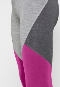 Grå och rosa träningsleggings med en färgblockerad design, där den övre delen är texturerad grå och den nedre delen är slät rosa.