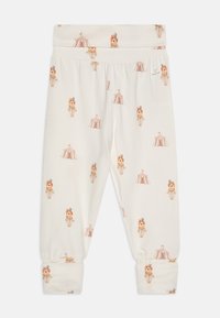 Leggings crème avec une taille élastique, ornés d'un motif de lions et de tentes de cirque. Tissu doux avec des chevilles côtelées.