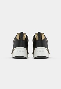 Czarno-złote sneakersy z teksturowaną cholewką, metalicznymi akcentami i białą podeszwą. Charakteryzują się markowym tyłem i sportowym designem.