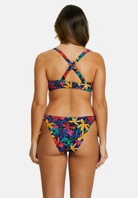 Ensemble de bikini floral avec un fond noir et des motifs de feuilles colorées. Le haut a des bretelles croisées dans le dos et le bas a un design taille basse.