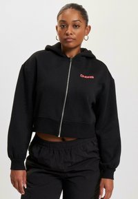 Black cropped hoodie with a front zipper, fitted cuffs, and a red graphic logo on the left chest. Soft fabric with a smooth texture.