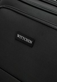 Valigia nera in tessuto con finitura testurizzata, due scomparti con zip e un'etichetta rettangolare nera con "WITTCHEN" in lettering argentato.