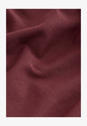 Tejido texturizado burdeos con una superficie acanalada, mostrando pliegues sutiles y una apariencia suave, ideal para aplicaciones de ropa o tapicería.