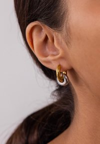 Gold- und Silberohrringe mit einem ineinandergreifenden Schlaufen-Design, einer polierten Oberfläche und glatter Textur. Für Ohrlöcher geeignet.