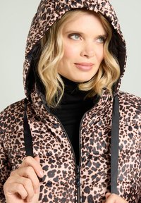 Chaqueta acolchada con estampado de leopardo en tonos rosa y negro, con capucha, cierre de cremallera y correas ajustables, que muestra una textura brillante.
