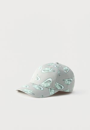 Casquette de baseball Nike gris clair avec motifs répétés du logo Nike vert clair imprimés partout, reposant sur une surface blanche.