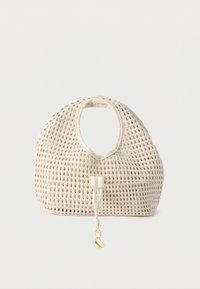 Τσάντα χειρός σε κρεμ απόχρωση με στρογγυλεμένες επάνω λαβές και ένα χρυσό κρεμαστό διακοσμητικό που κρέμεται από το μπροστινό κορδόνι.