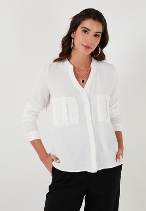 White button-up blouse with a mandarin collar, two front pockets, long sleeves, and a lightweight textured fabric.